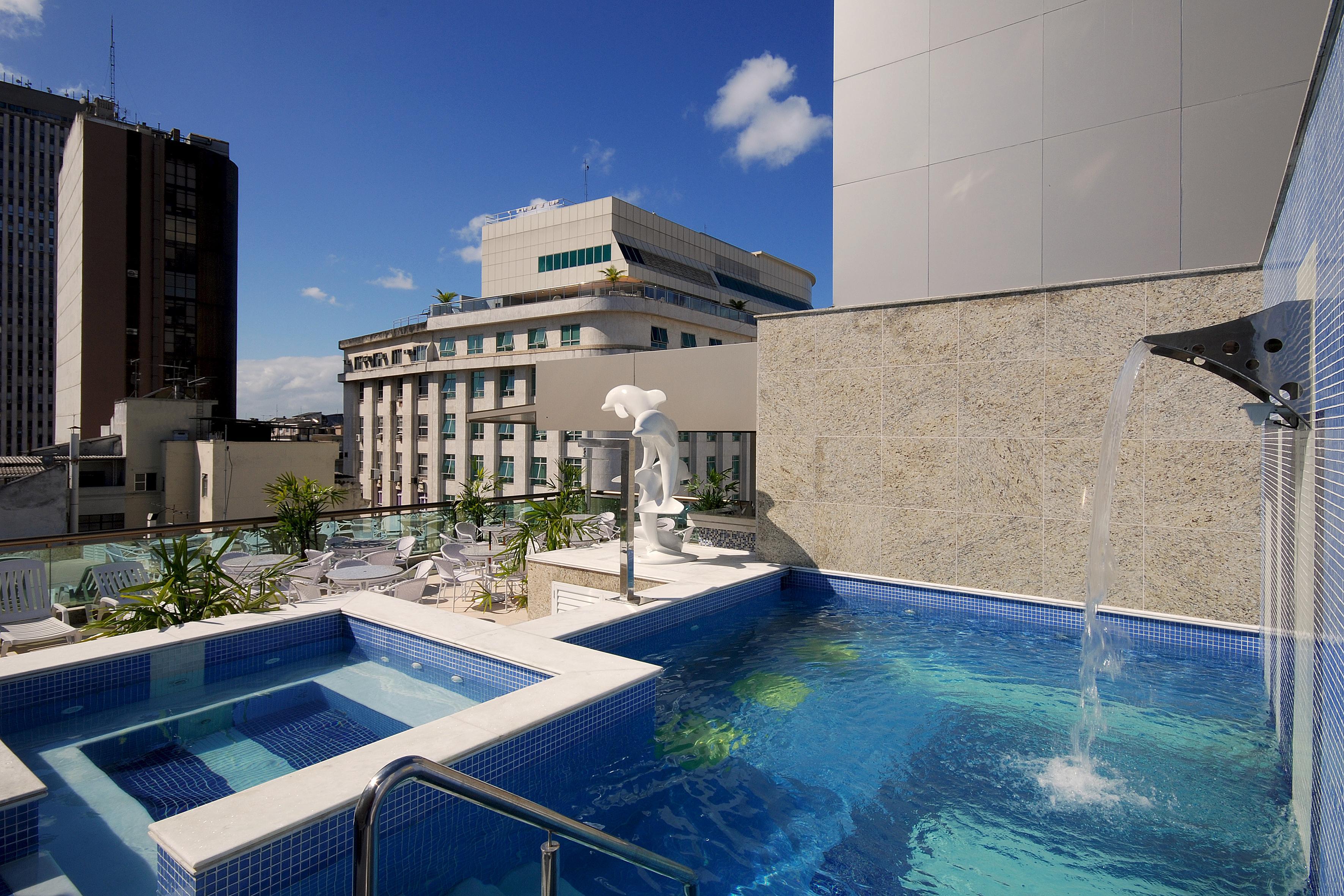 Hotel Atlântico Business Centro Río de Janeiro Exterior foto The photo shows a rooftop area featuring a swimming pool and a spa. The pool is inviting with a clear blue water, and there appears to be a waterfall feature. Surrounding the pool are areas for relaxation, possibly with sun loungers. In the backgroun